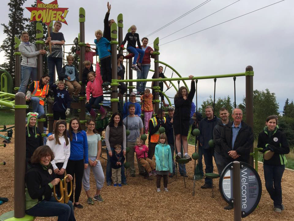 Large group on gathered playset at Moen Park with Neighbor Power sign