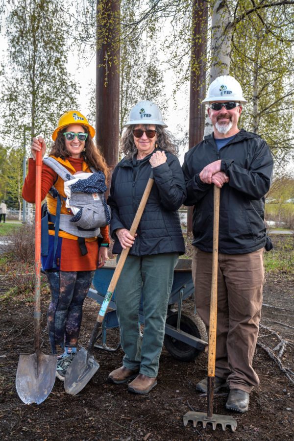 Three volunteers wearing YEP hard hats and holding shovels